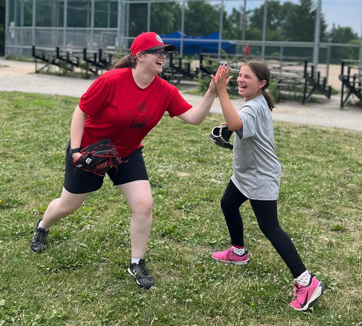 Baseball coach hi-fiving a player at camp