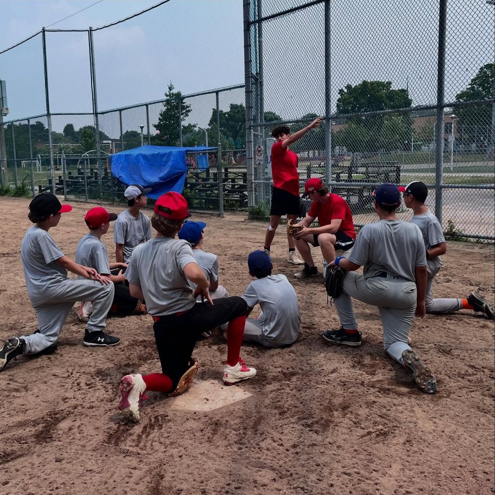 Day camp baseball players on one knee listening to coach